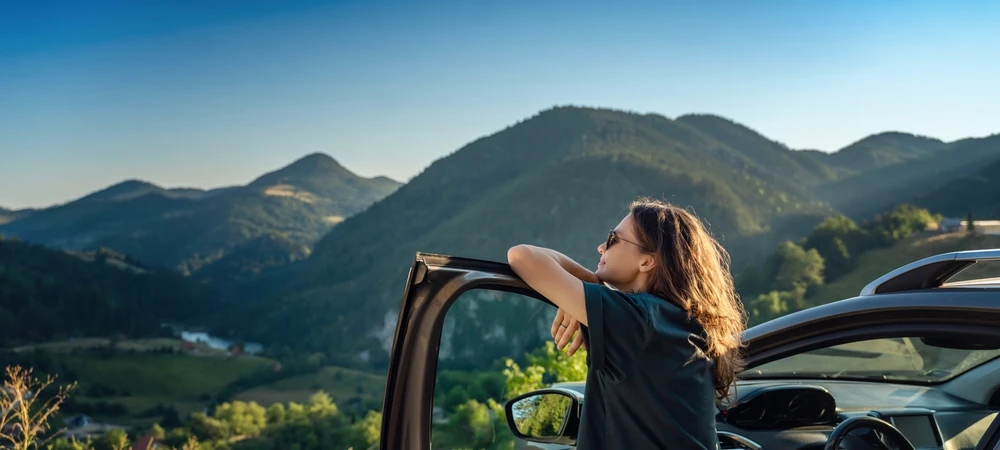 Femme sortant de sa voiture et regardant les montagnes